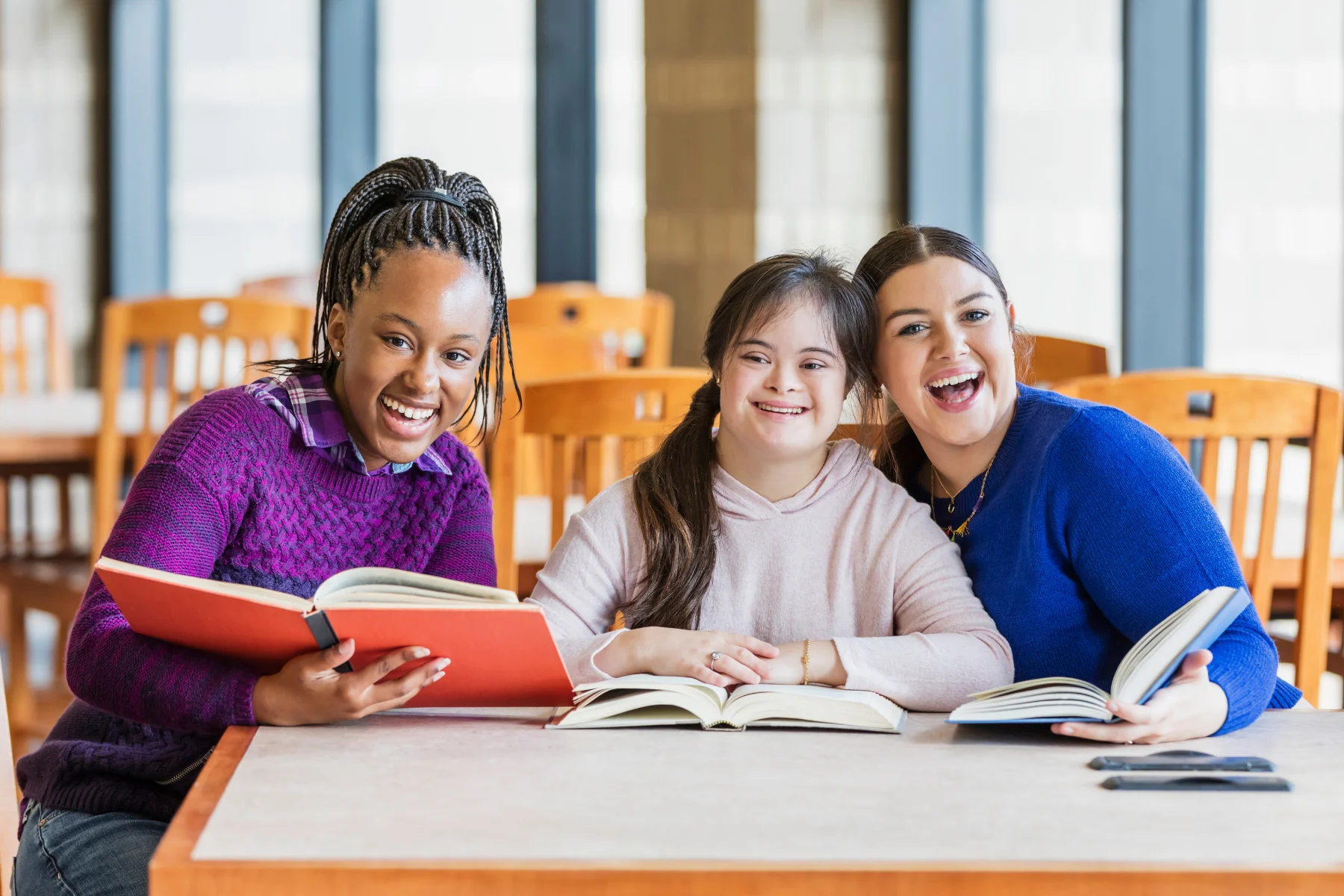 Three happy girls reading a book